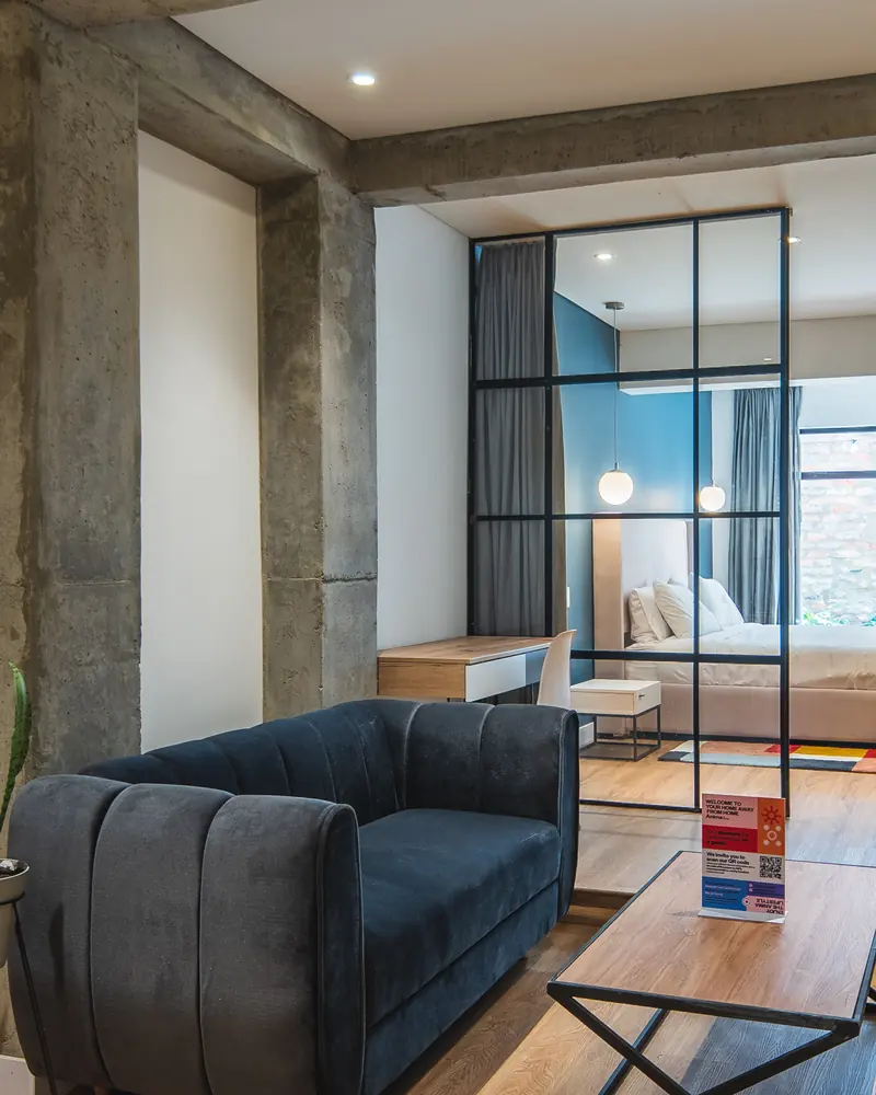 Apartamento de Anima 65 con columnas de concreto, sala y alcoba tras un vidrio