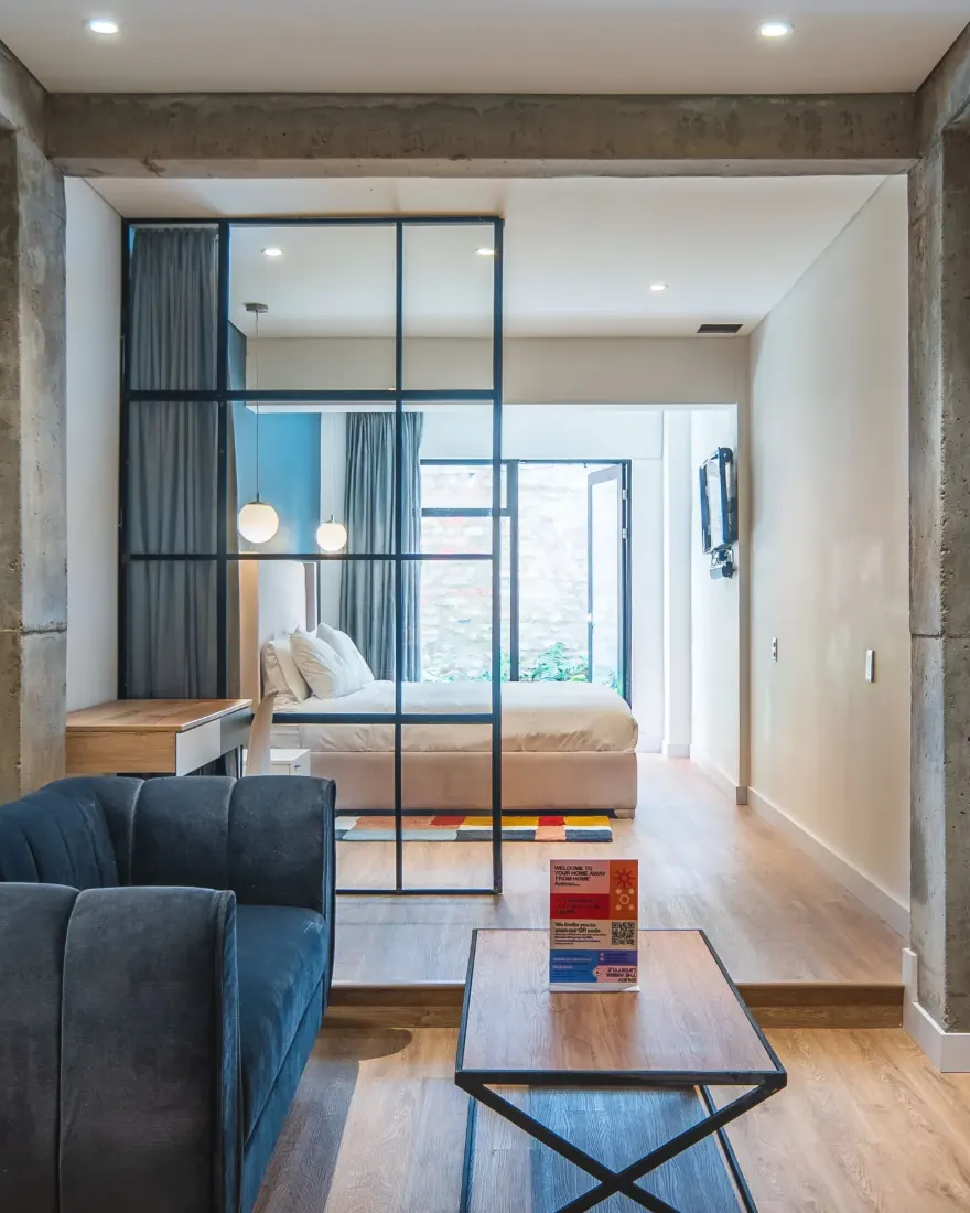 Apartamento de Anima 65 con columnas de concreto, sala y alcoba tras un vidrio