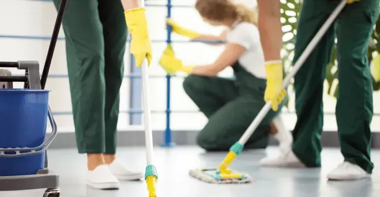 Equipo de limpieza profesional trapeando y ordenando un apartamento
