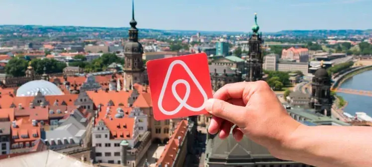 Vista de una ciudad europea con una tarjeta de Airbnb en primer plano