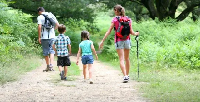 Familia caminando por un sendero rodeado de vegetación
