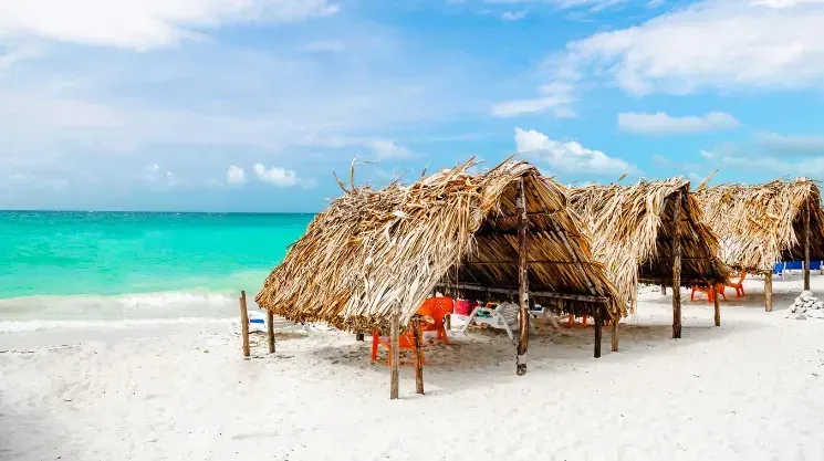 Kioscos de palma sobre arena blanca y mar turquesa en Playa Blanca