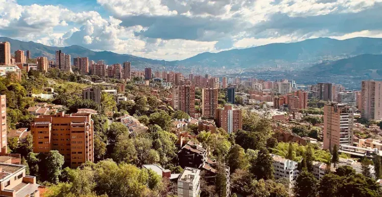 Vista de Medellín con edificios entre montañas verdes