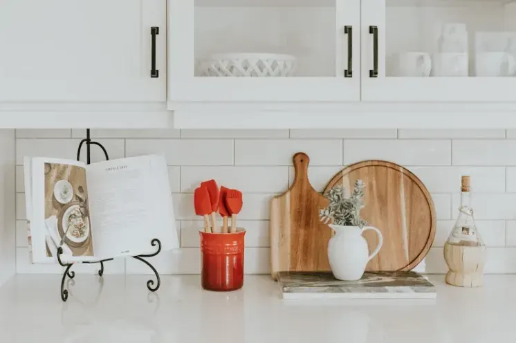 Cocina blanca equipada con tablas de madera, utensilios y especias