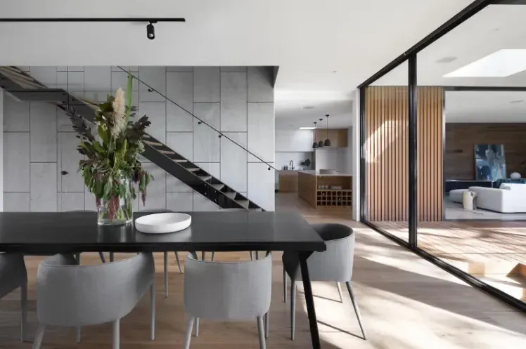Espacio minimalista con escalera, planta y grandes ventanales