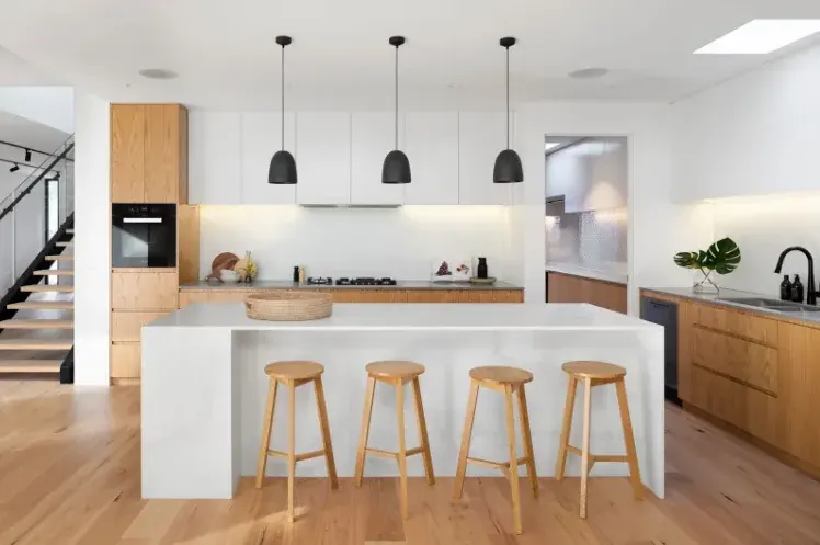 Sala moderna con muebles claros, piso de madera y ventanales de piso a techo